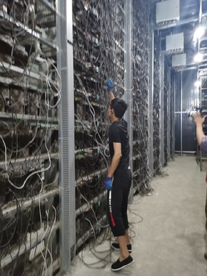 A large scale mining farm filled with rows of mining rigs is shown
